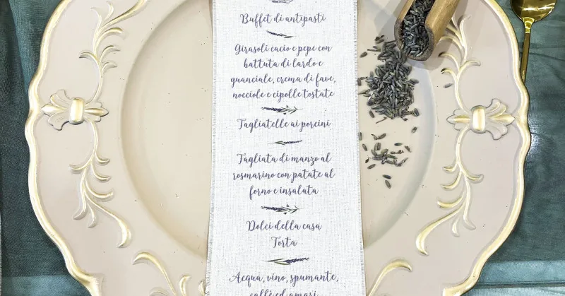 Menu stampato su una striscia di lino, appoggiato su un piatto con fiori di lavanda